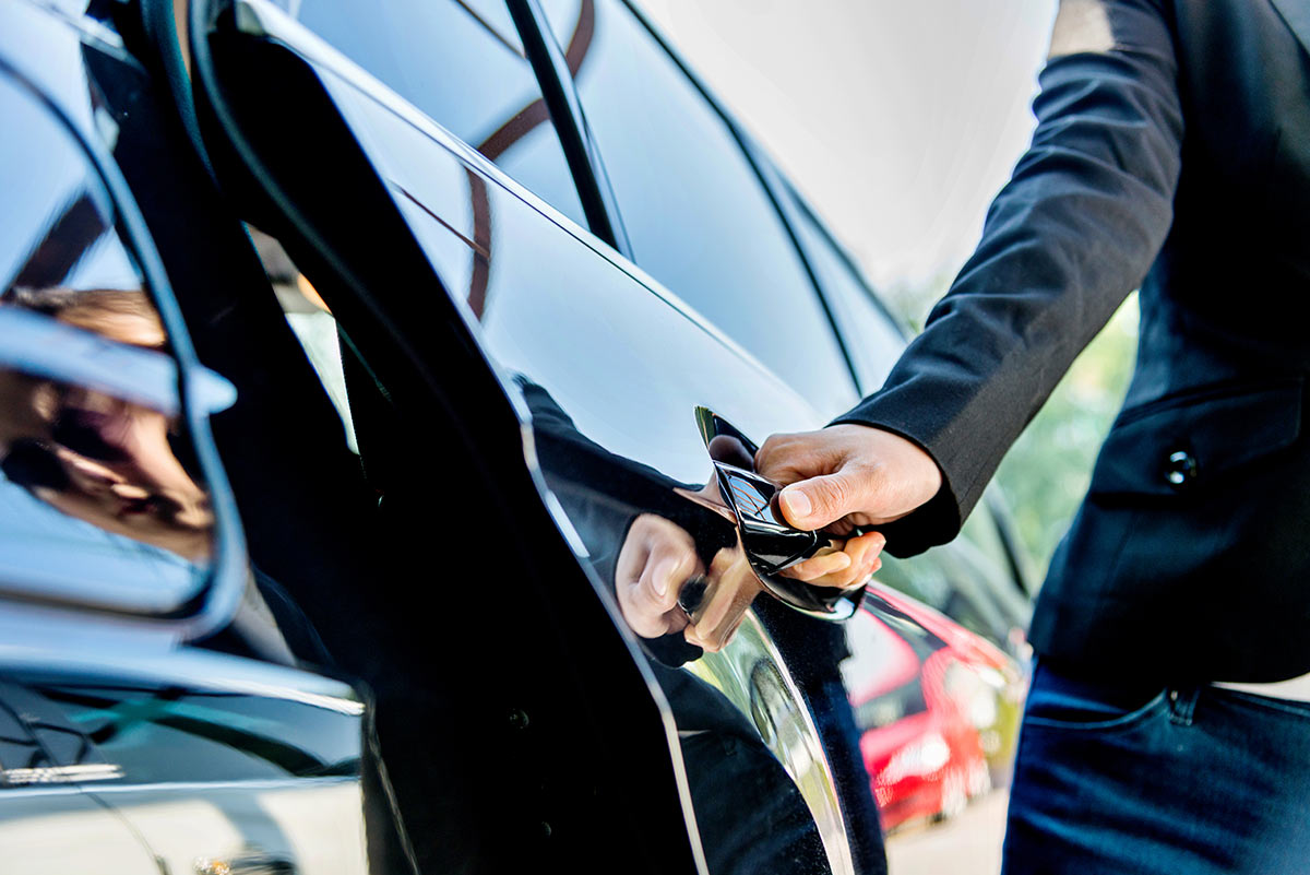 Hombre abriendo la puerta de un auto negro 