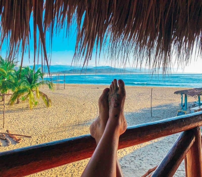 pies de mujer en una barandilla en una cabaña tropical frente al mar en chacahua, oaxaca, méxico | Las mejores playas de Oaxaca