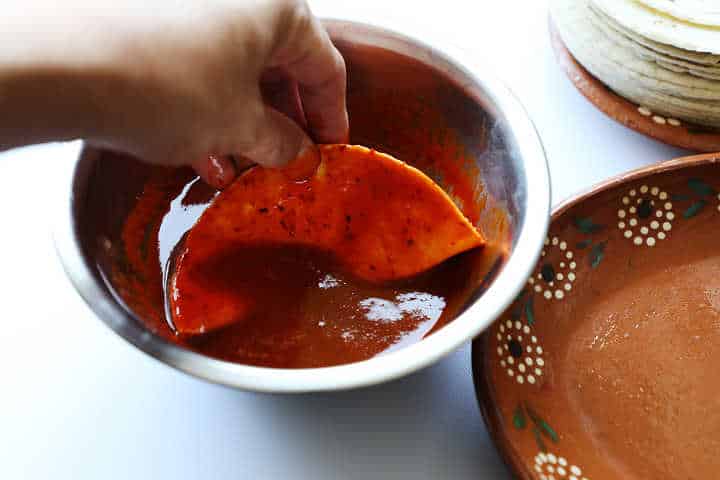 Mojando tortilla de maíz en salsa de chile guajillo.