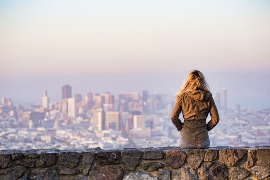 Chica en la pared mirando el paisaje urbano